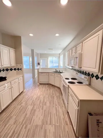 a kitchen with a sink wooden floor and white appliances