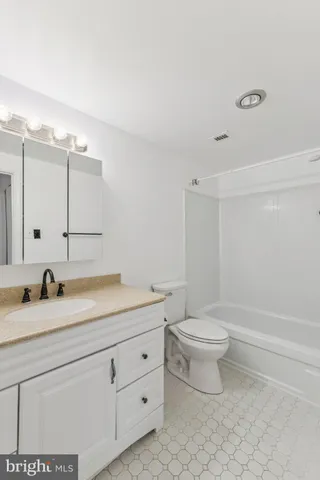 a bathroom with a granite countertop sink a toilet and a bathtub