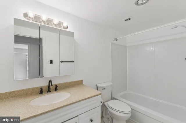 a bathroom with a granite countertop sink toilet a mirror and shower