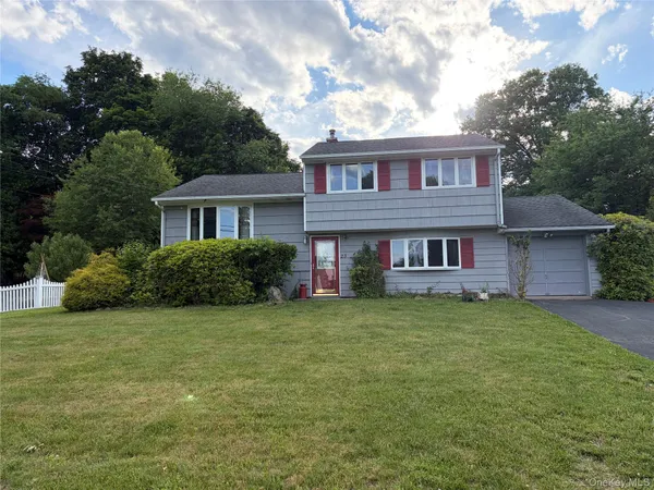 a view of a house with a yard plants and large tree