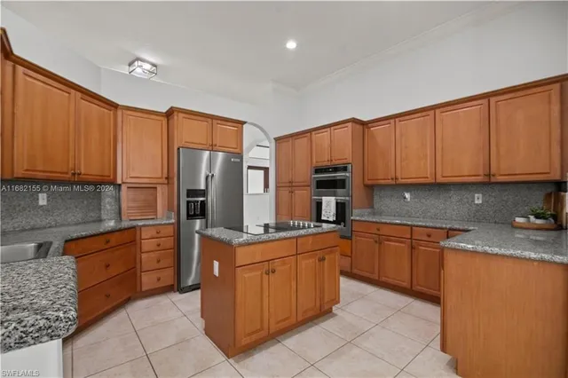 a kitchen with stainless steel appliances granite countertop a stove top oven a sink dishwasher and a refrigerator