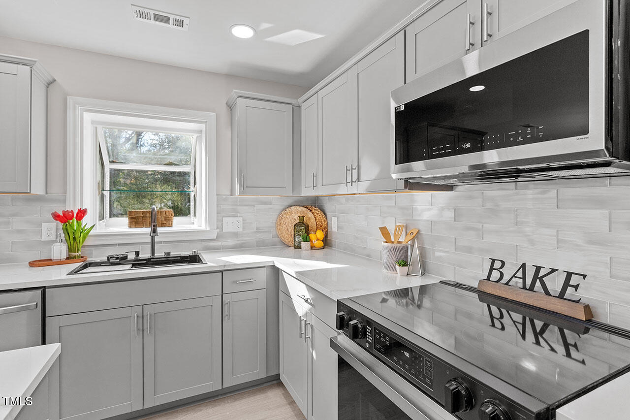 1014 Southerlund Road Garner, NC 27529 - Photo 12 of 36 a kitchen with stainless steel appliances a sink a stove and a microwave