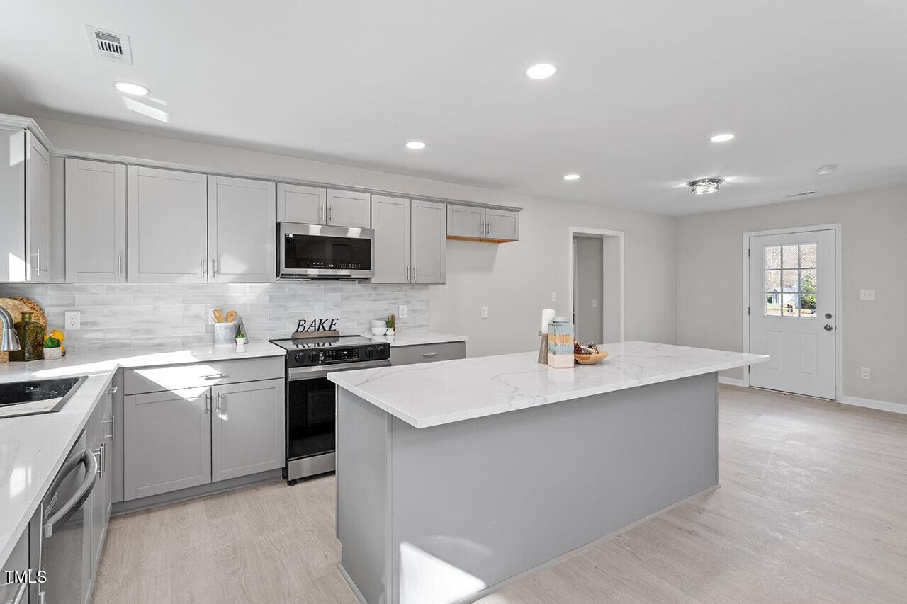 1014 Southerlund Road Garner, NC 27529 - Photo 13 of 36 a kitchen with a sink stainless steel appliances and white cabinets
