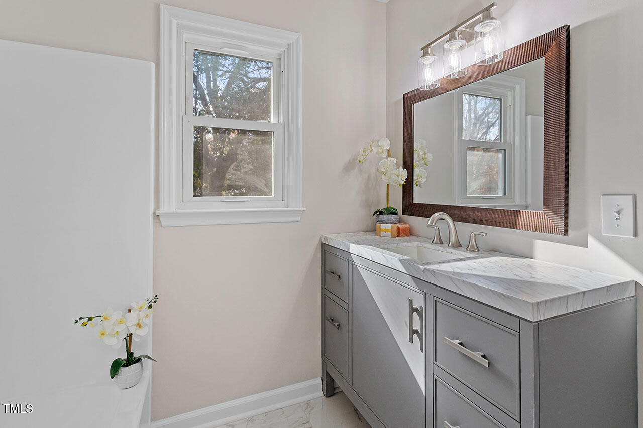 1014 Southerlund Road Garner, NC 27529 - Photo 28 of 36 a bathroom with a granite countertop sink a mirror and a window