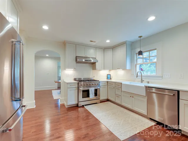 a large kitchen with cabinets wooden floor and stainless steel appliances