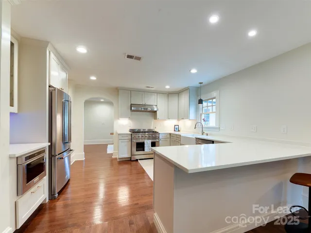 a large kitchen with a large counter top stainless steel appliances and cabinets
