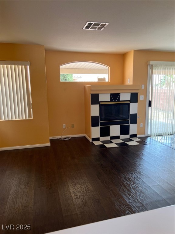 212 Silver Castle Street Las Vegas, NV 89144 - Photo 5 of 24 Unfurnished living room featuring visible vents, a tile fireplace, baseboards, and wood finished floors