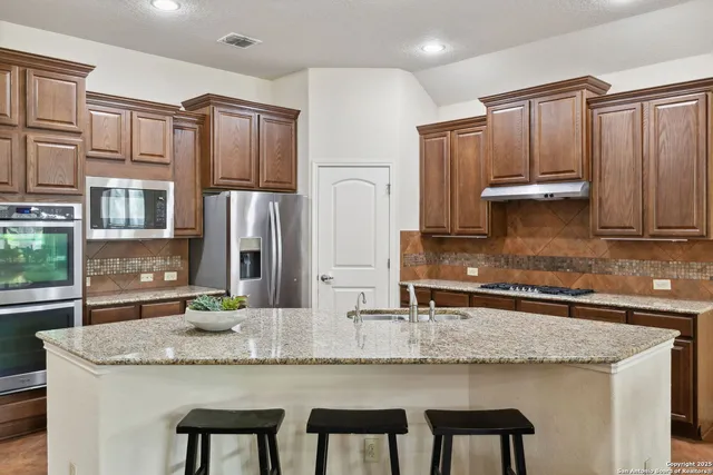 a kitchen with granite countertop stainless steel appliances and wooden cabinets