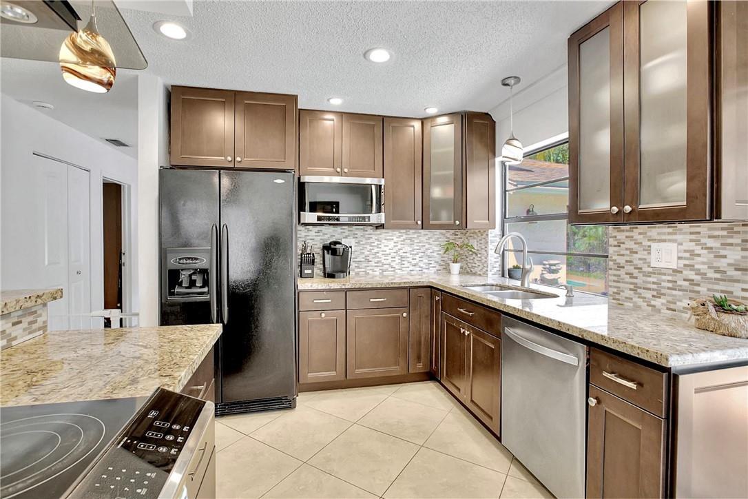 106 Kensington Road Hollywood, FL 33021 - Photo 18 of 42 a large kitchen with stainless steel appliances kitchen island granite countertop a refrigerator and a sink