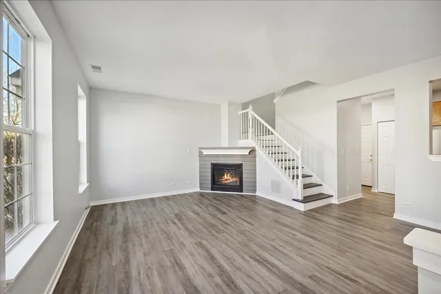 a view of a livingroom with wooden floor fireplace and windows