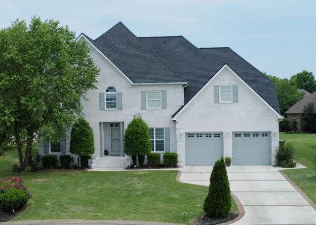 a front view of a house with a garden and trees