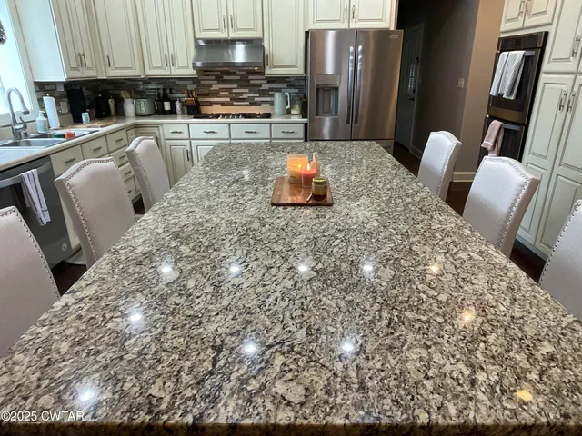 a kitchen with stainless steel appliances kitchen island granite countertop a table and chairs