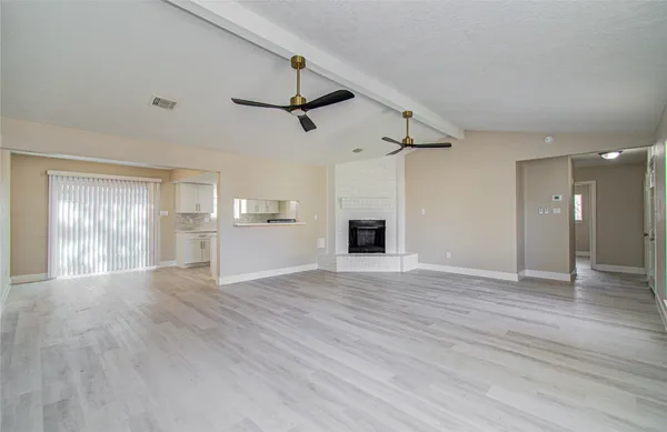 a view of empty room with wooden floor and ceiling fan