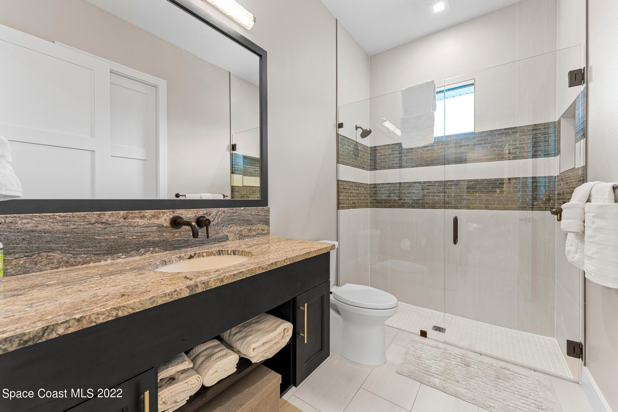 4574 Milost Drive Rockledge, FL 32955 - Photo 20 of 41 a bathroom with a granite countertop sink a toilet a mirror and shower