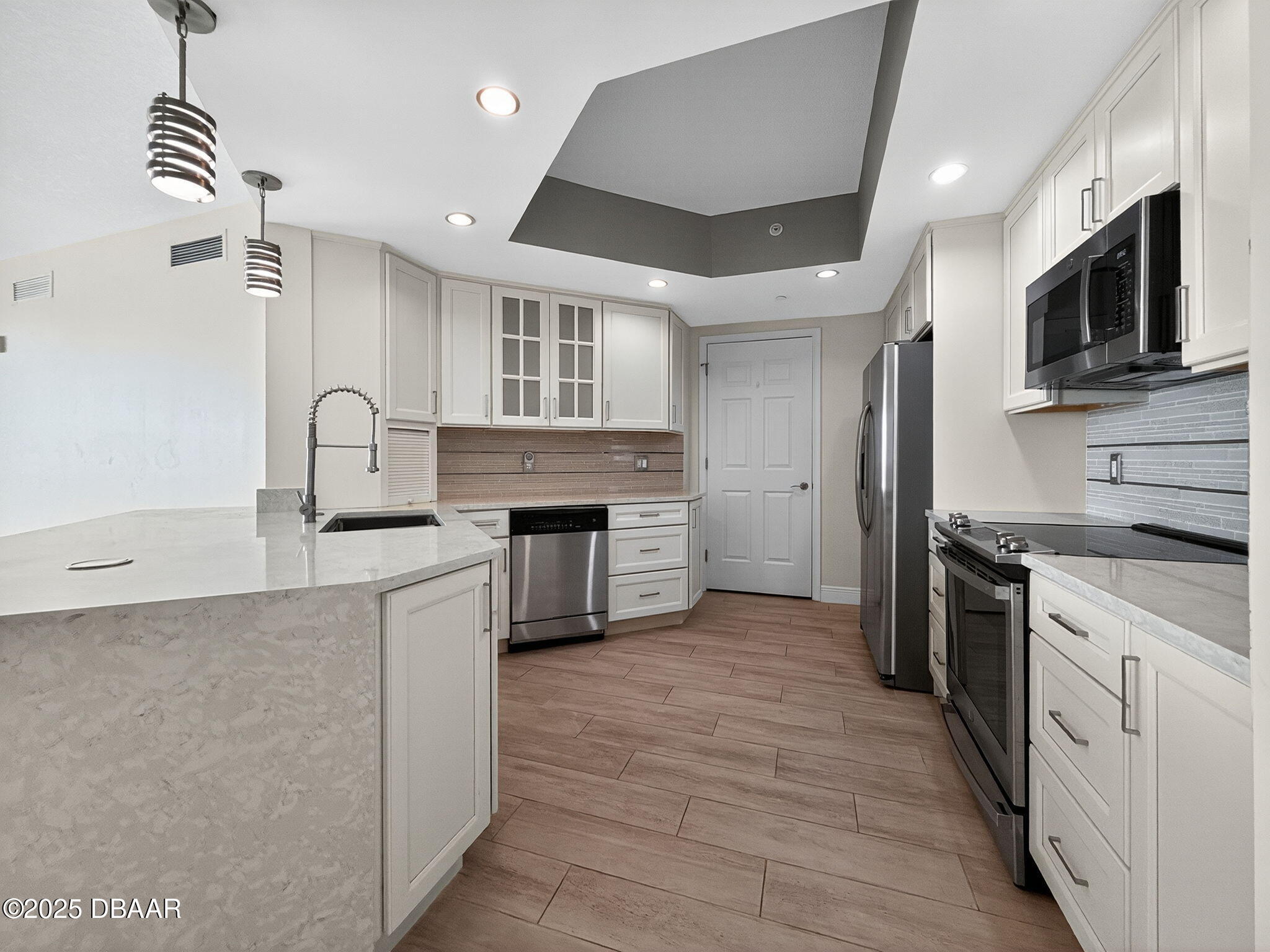 231 Riverside Drive, Unit 903 Holly Hill, FL 32117 - Photo 24 of 28 a kitchen with stainless steel appliances granite countertop a stove top oven a sink dishwasher and a refrigerator with wooden floor
