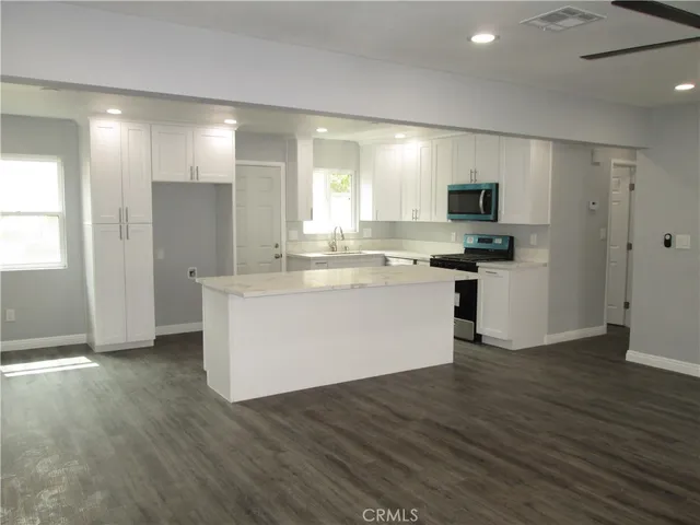 a view of kitchen with microwave stove refrigerator and cabinets
