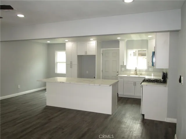 a large white kitchen with wooden floors and white walls