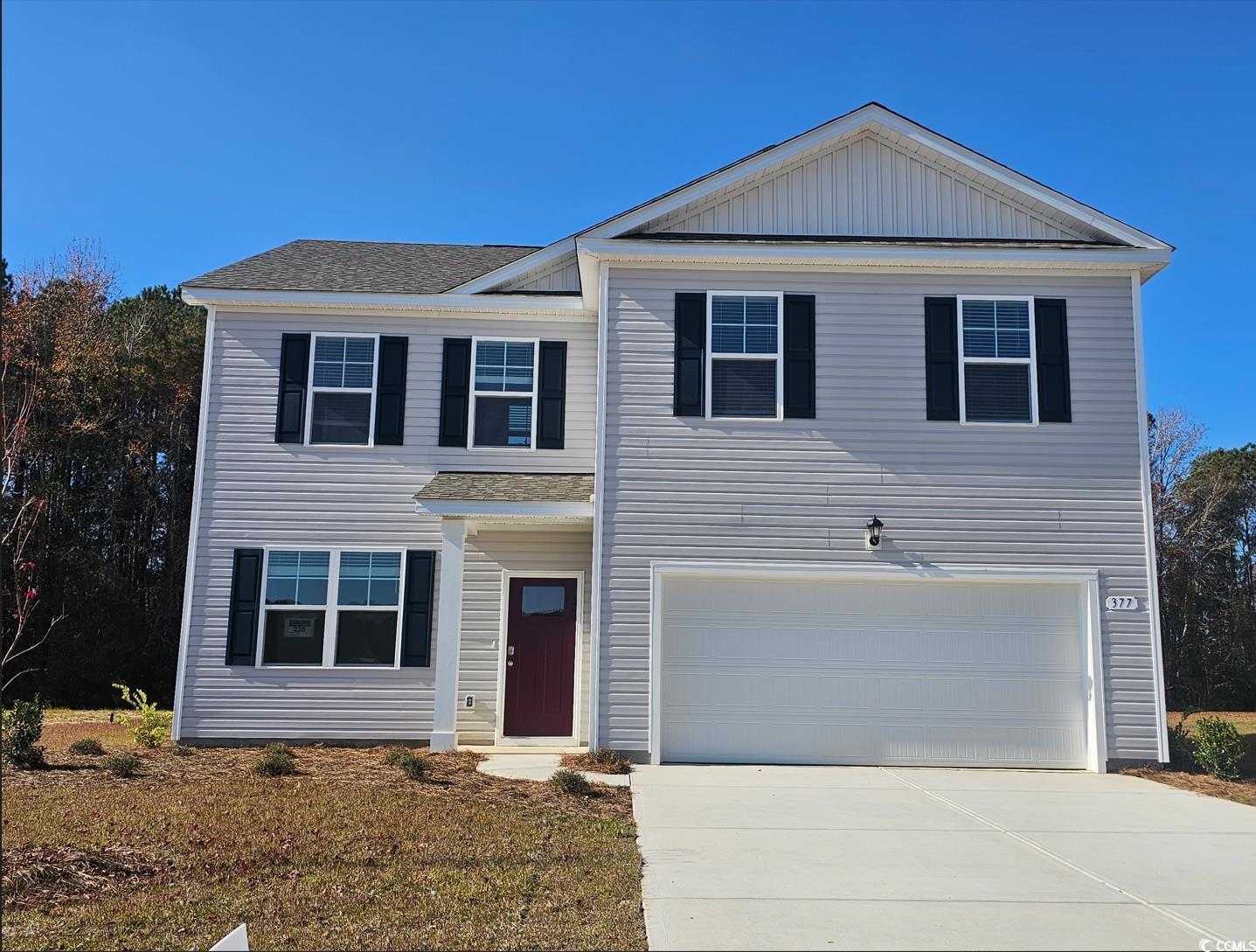 View of front of home featuring concrete driveway, an attached garage, a shingled roof, and board and batten siding