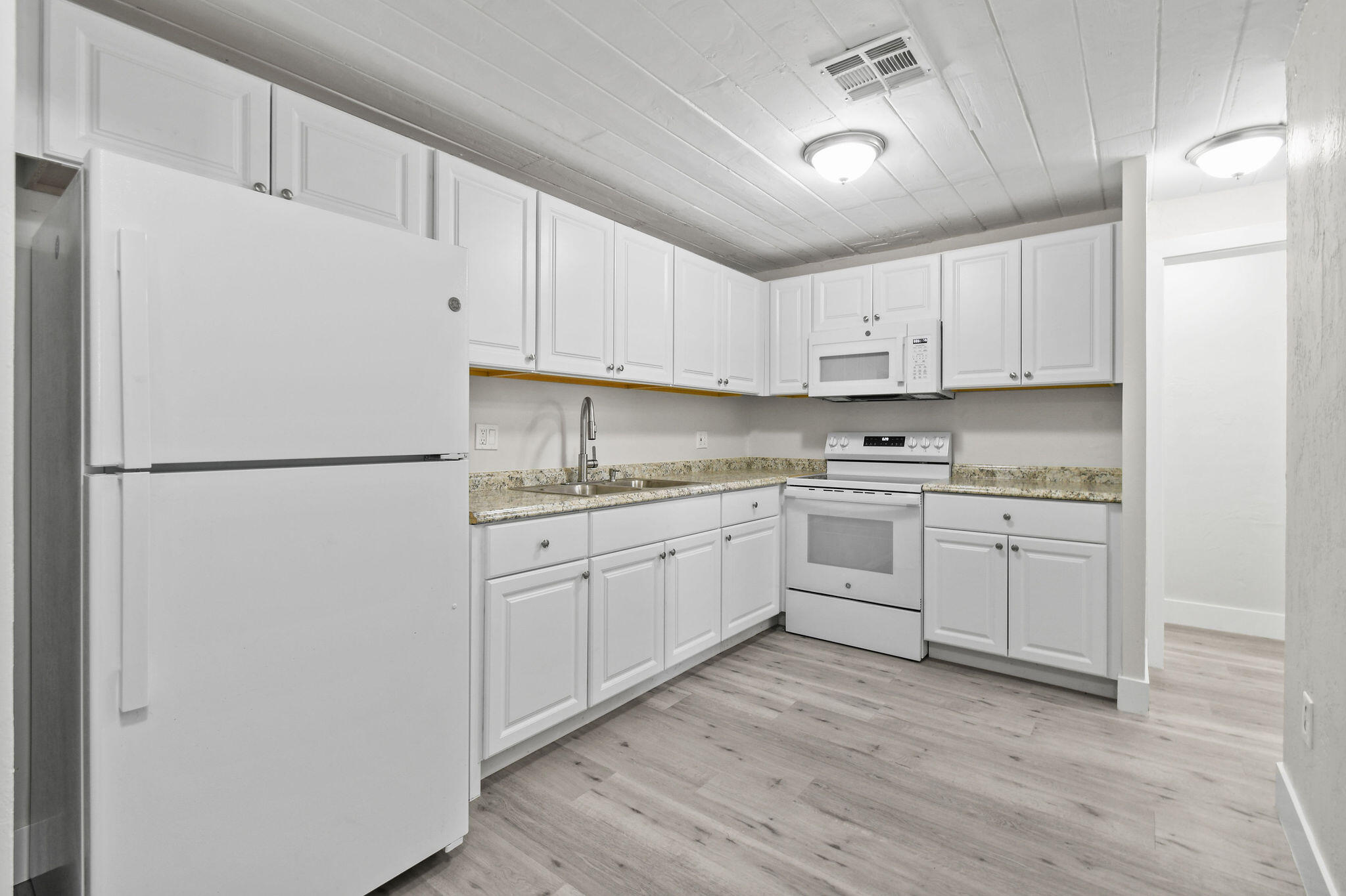 1301 West 25th Street Riviera Beach, FL 33404 - Photo 8 of 34 a kitchen with white cabinets and white appliances