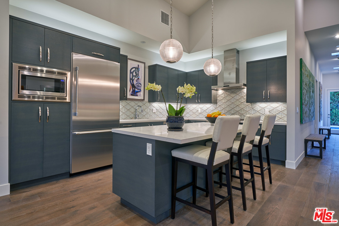 11622 Addison Street Valley Village, CA 91601 - Photo 14 of 39 a kitchen with stainless steel appliances a dining table chairs and refrigerator