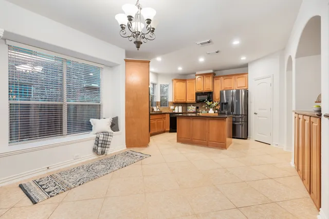 a large kitchen with stainless steel appliances kitchen island granite countertop a refrigerator and a sink