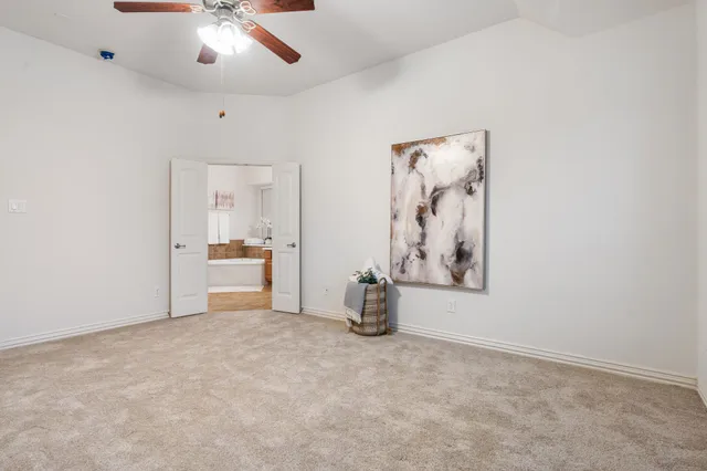 an empty room with chandelier fan and windows