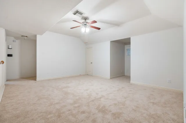 an empty room with a chandelier fan and closet