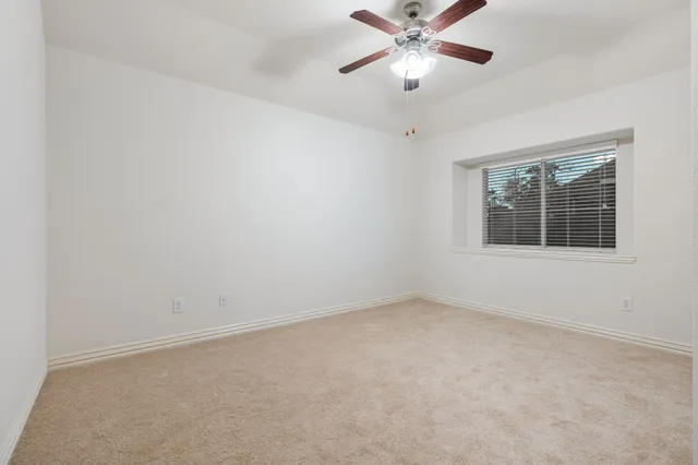 an empty room with a window and a ceiling fan
