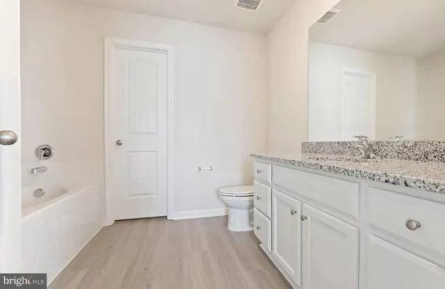 a spacious bathroom with a granite countertop sink a toilet and shower