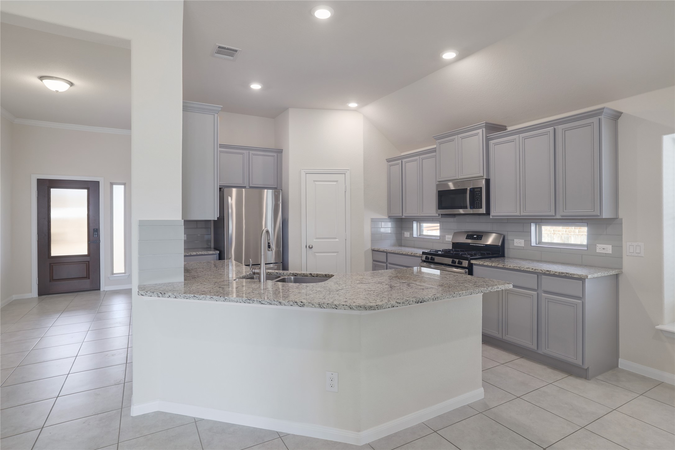 3341 Pauling Loop Round Rock, TX 78665 - Photo 12 of 40 Kitchen featuring backsplash, gray cabinetry, stainless steel appliances, a peninsula, and crown molding
