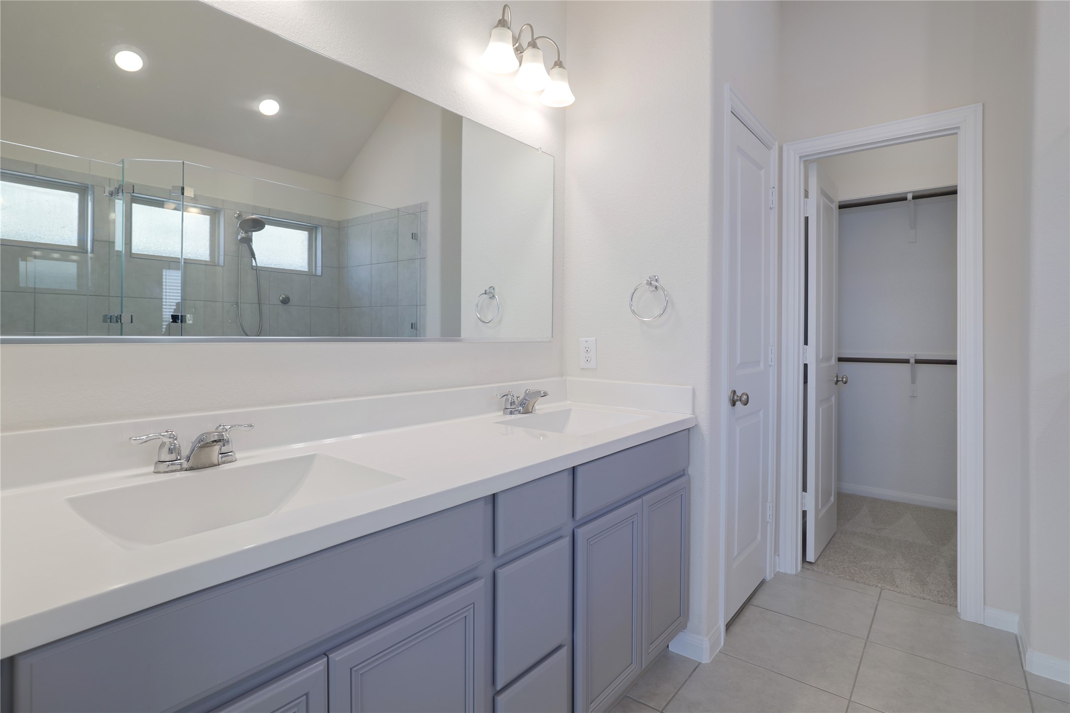 3341 Pauling Loop Round Rock, TX 78665 - Photo 18 of 40 Master Bathroom featuring an oversized shower, double vanity, lofted ceiling, a walk in closet, and light tile patterned floors