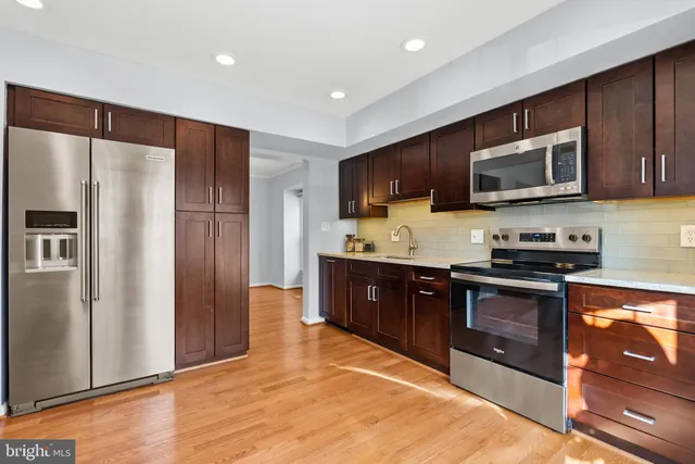 a large kitchen with stainless steel appliances granite countertop a stove a refrigerator and a microwave