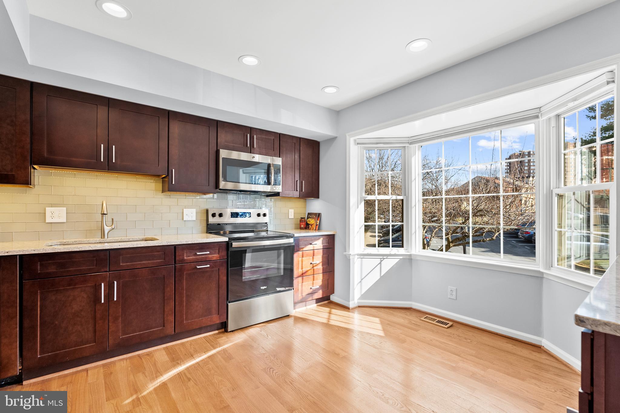 5465 Grove Ridge Way, Unit 123 Rockville, MD 20852 - Photo 10 of 39 a large kitchen with stainless steel appliances granite countertop a stove top oven a sink dishwasher a microwave oven and a refrigerator with wooden cabinets