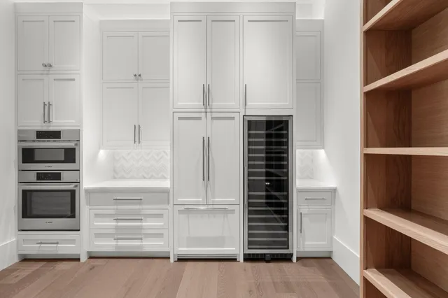 an empty room with wooden floor cabinet and windows