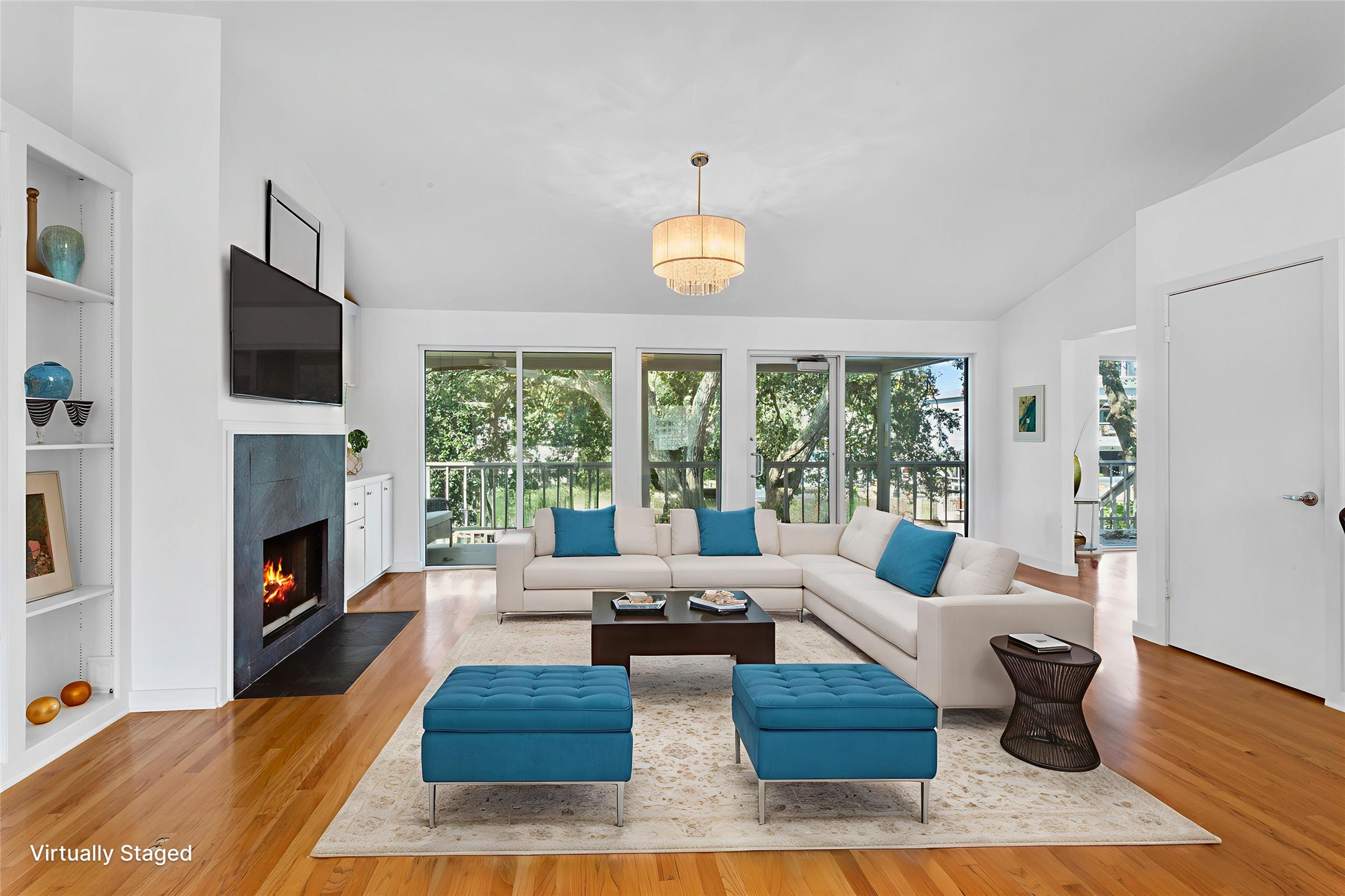67 Harbor Lane Kemah, TX 77565 - Photo 5 of 47 Bright and airy living room with a modern open design, featuring large, floor to ceiling windows, a cozy fireplace, and light wood flooring. The neutral palette with blue accents complements the comfortable sectional and stylish décor, creating an inviting atmosphere. (Staged Photo)
