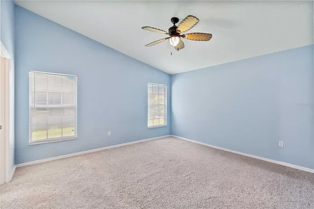 an empty room with windows and fan