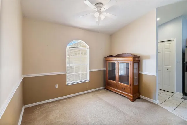 an empty room with windows and ceiling fan