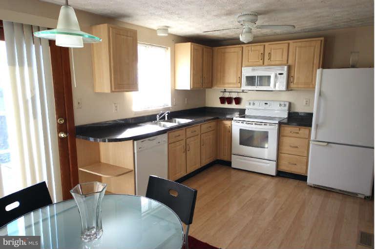 522 Fuselage Avenue Baltimore, MD 21221 - Photo 4 of 16 a kitchen with stainless steel appliances a stove a sink dishwasher a refrigerator white cabinets and wooden floor