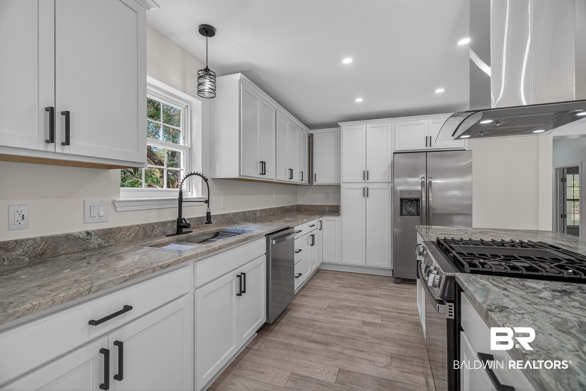 10650 Old Pascagoula Road Theodore, AL 36582 - Photo 25 of 77 Kitchen with stainless steel appliances, island range hood, light stone counters, white cabinetry, and hanging light fixtures