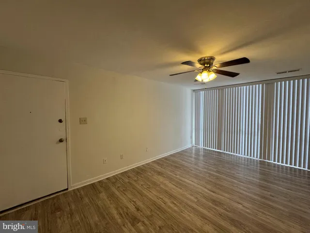 an empty room with wooden floor fan and windows