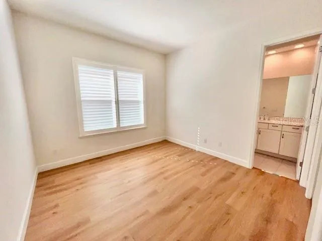 an empty room with wooden floor and a kitchen