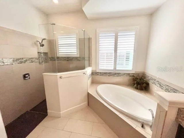 a bathroom with a bathtub a sink a window and a shower