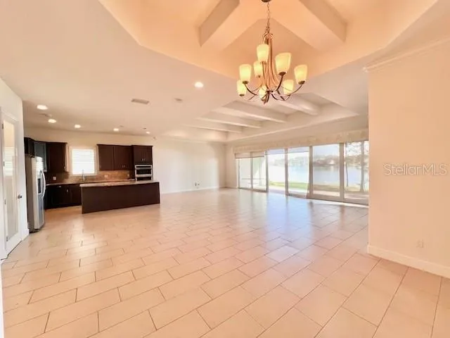 a view of a kitchen with kitchen island stainless steel appliances a stove a refrigerator a sink dishwasher with a dining table and chairs with wooden floor