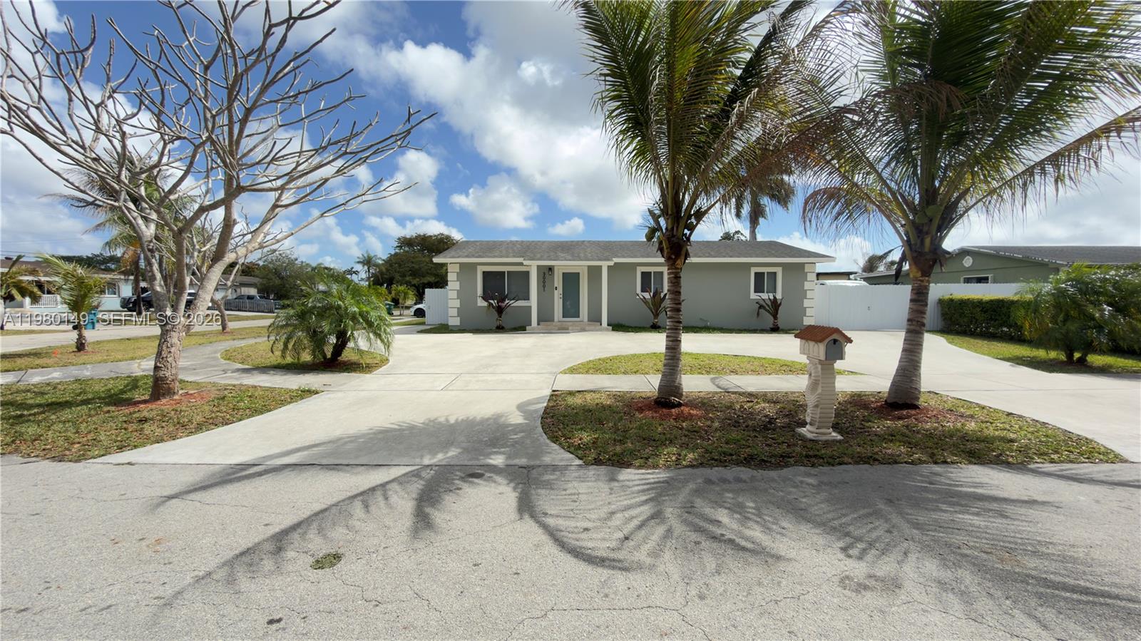 a front view of a house with garden and tree
