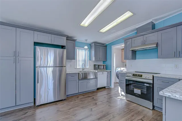 a view of a kitchen with a refrigerator a sink and wooden floor