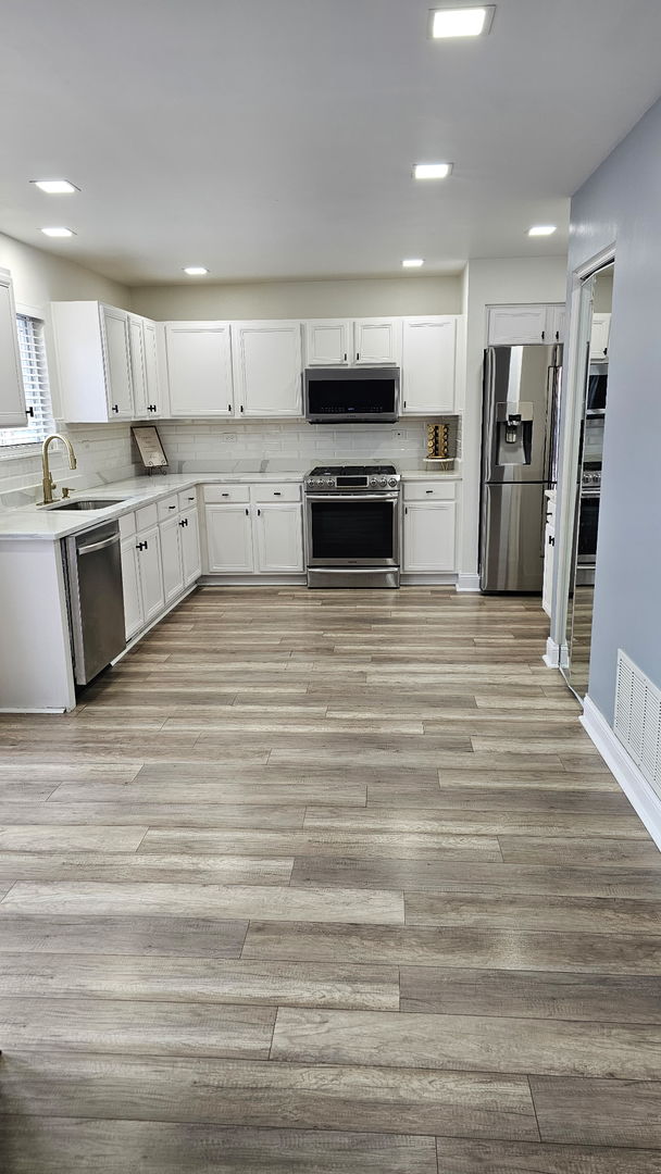 2214 Andrew Trail Montgomery, IL 60538 - Photo 8 of 28 a large kitchen with cabinets wooden floor and stainless steel appliances