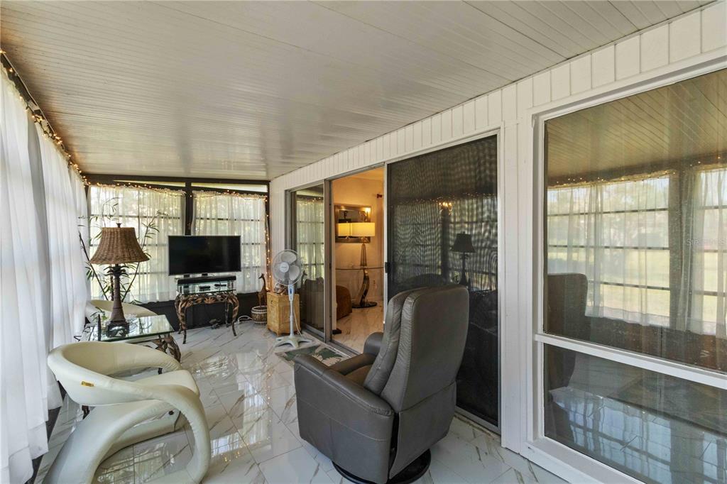 672 White Pine Tree Road, Unit 57 Venice, FL 34285 - Photo 16 of 57 a living room with furniture a flat screen tv and large windows