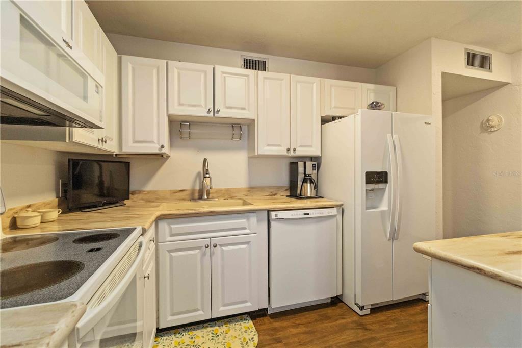 672 White Pine Tree Road, Unit 57 Venice, FL 34285 - Photo 9 of 57 a kitchen with stainless steel appliances granite countertop a refrigerator sink and white cabinets