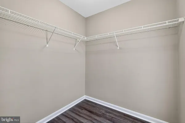 a view of an empty room with wooden floor and closet