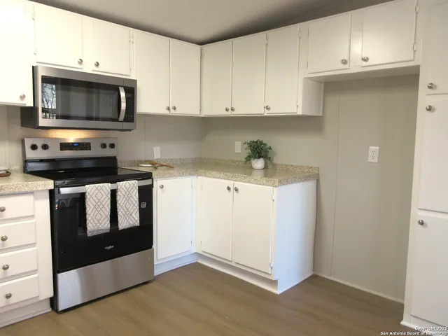 a kitchen with granite countertop white cabinets and black appliances